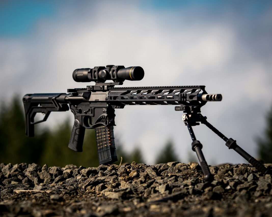 black rifle with scope on brown soil