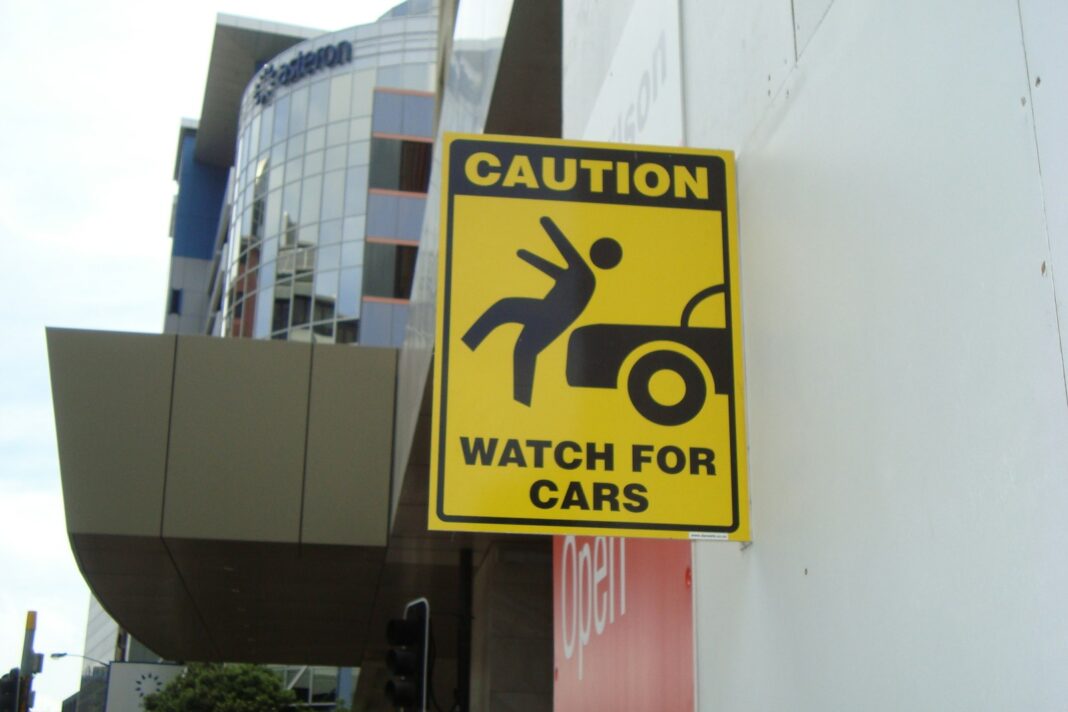 a yellow caution sign hanging on the side of a building