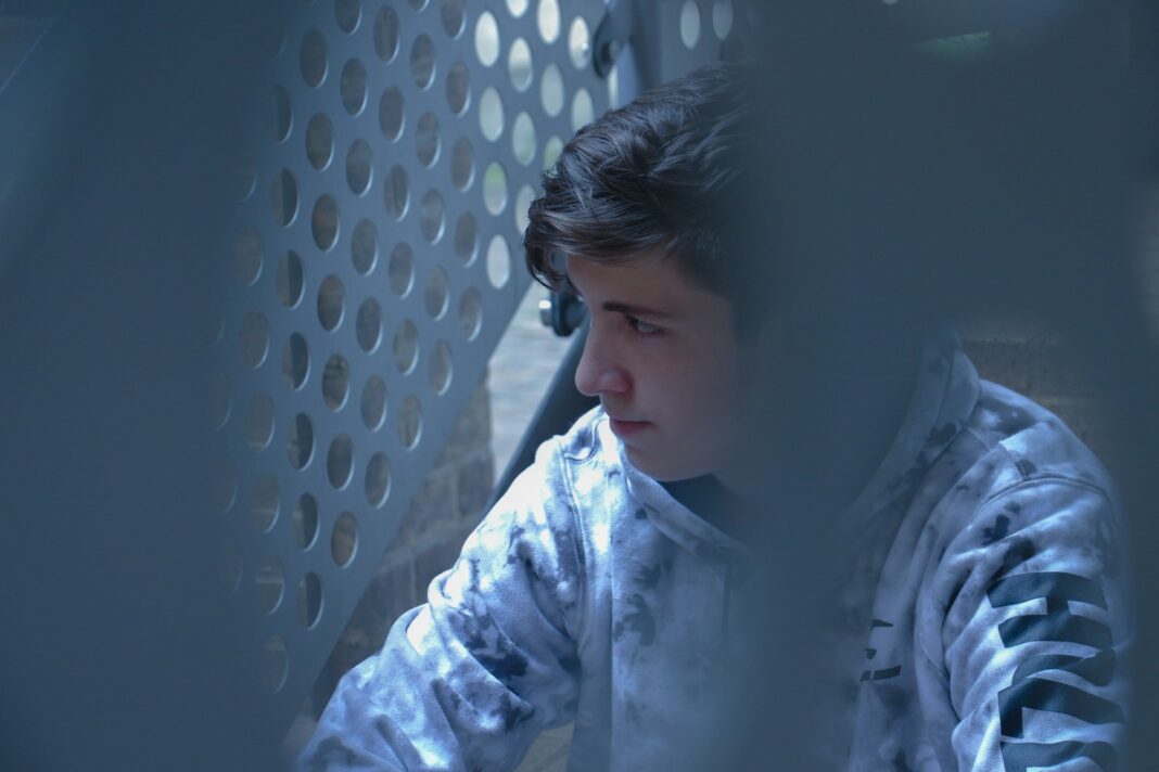man in black and white hoodie beside white grill
