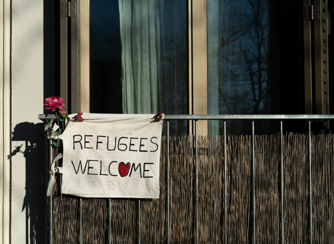 a sign that says refugees welcome on a building