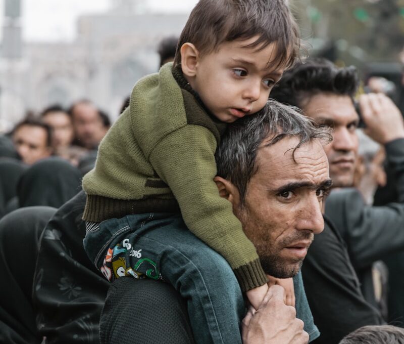 a man carrying a child on his shoulders