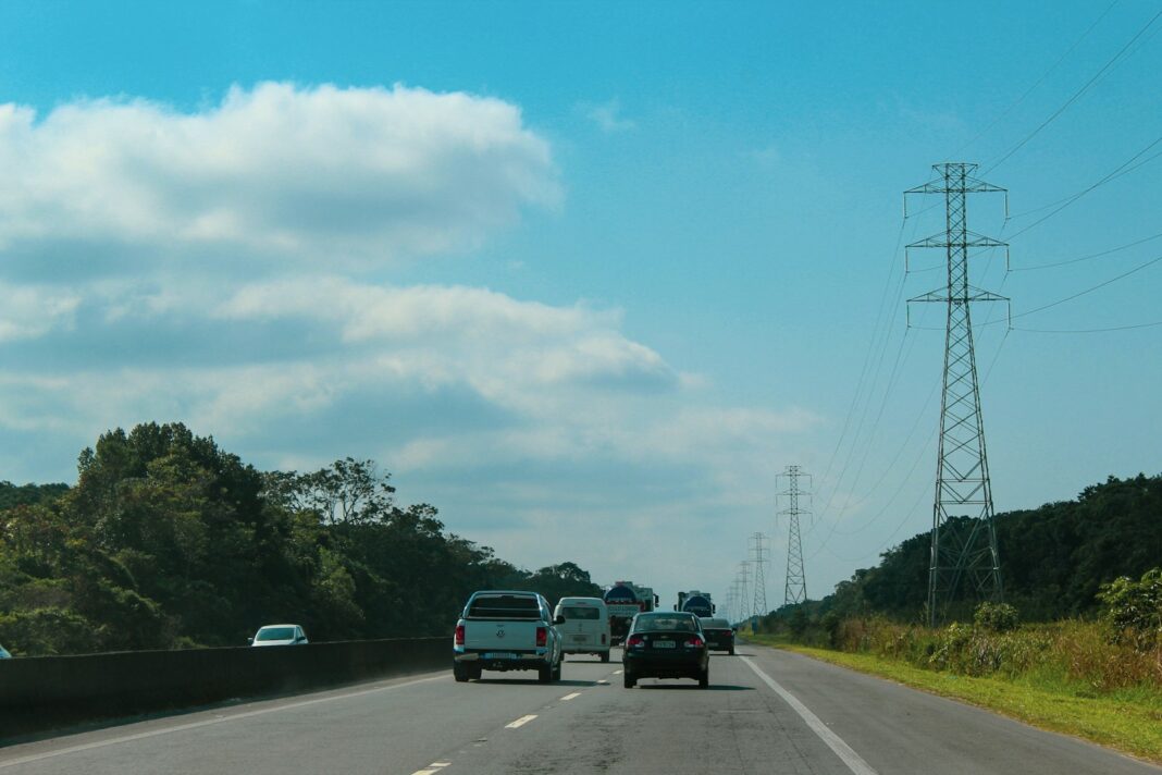 Cars driving on a highway under a blue sky.