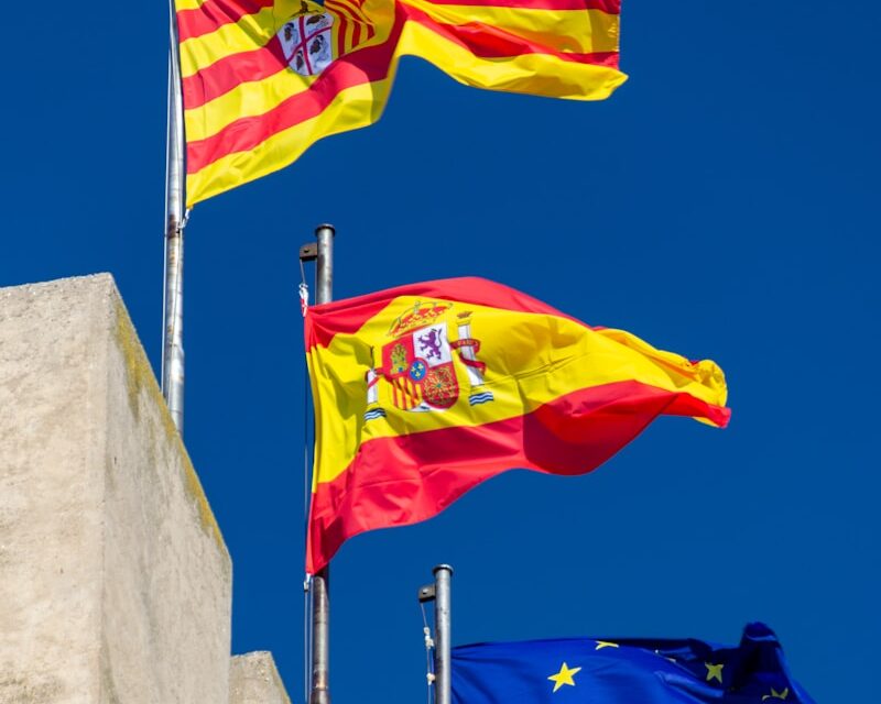 three flags flying in the wind on a sunny day