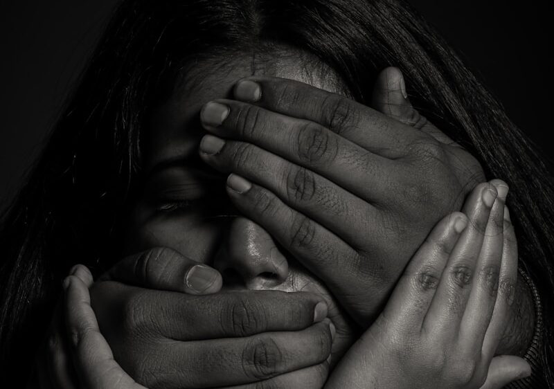 grayscale photo of woman covering her face with her hands