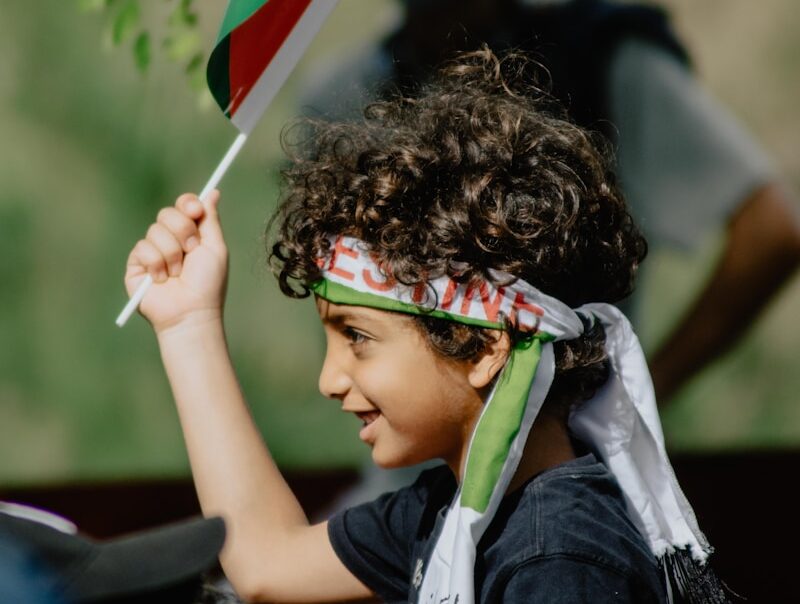 boy in blue and white shirt holding flag of us a during daytime
