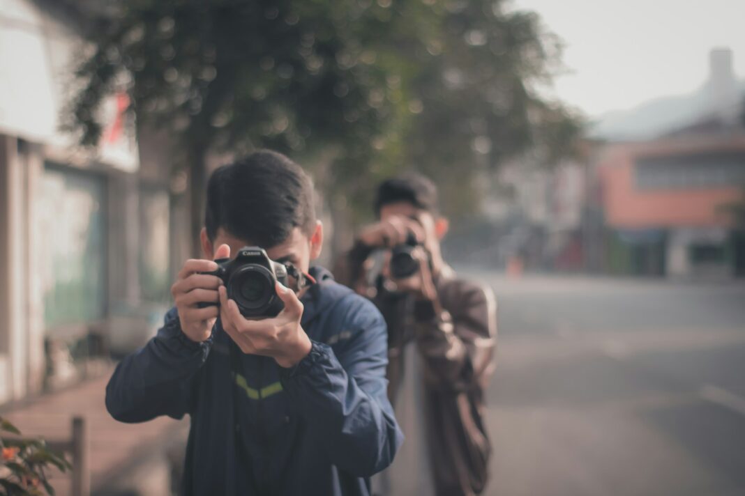 man in black jacket holding black dslr camera