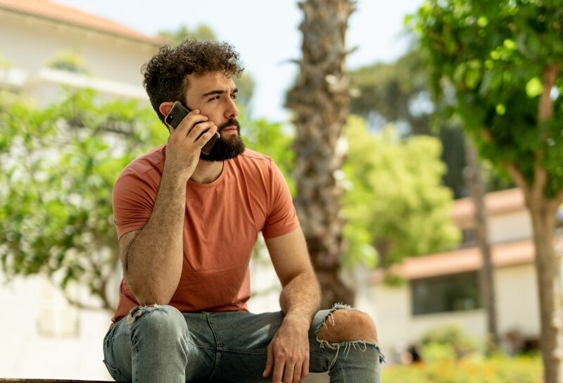 a man sitting on a bench talking on a cell phone