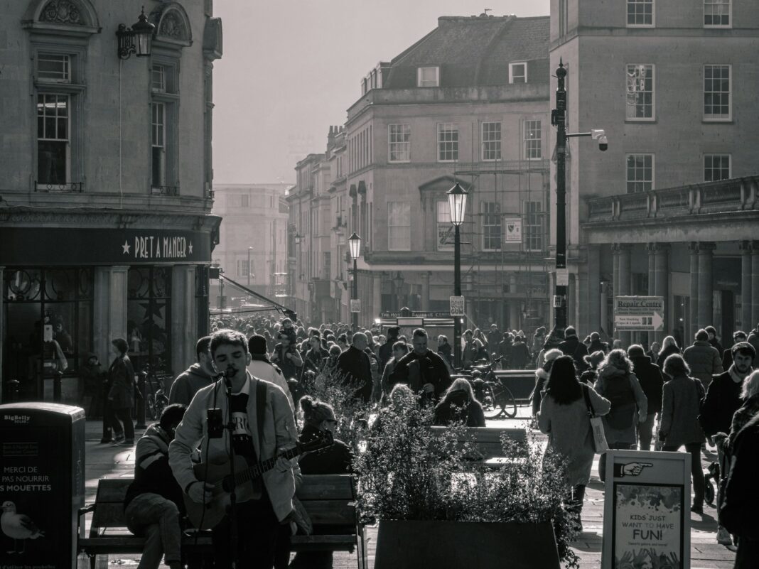 a crowd of people walking down a street next to tall buildings