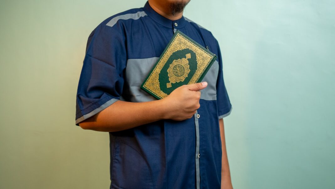 a man wearing a blue shirt and holding a book