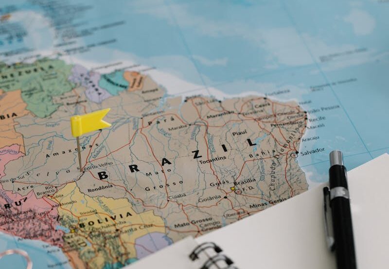 Close-up of Brazil on a world map with a notebook and pen for trip planning.