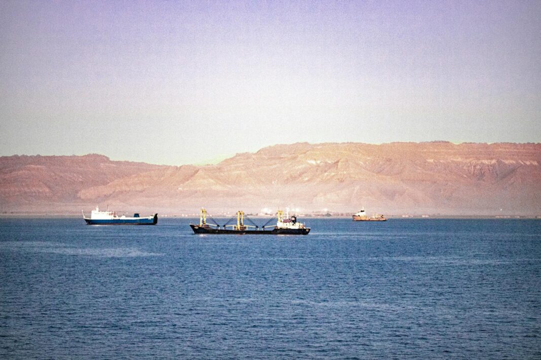 Serene view of cargo ships navigating the Suez Canal with mountains in the background.