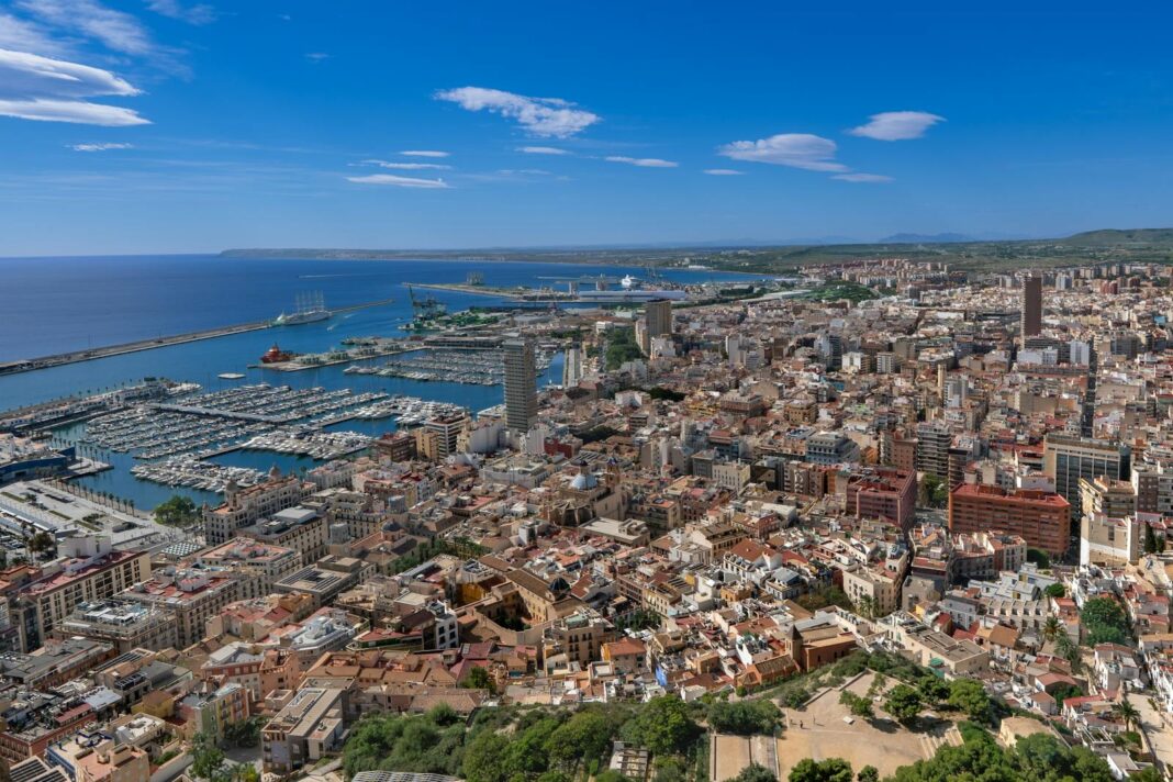 Aerial view of Alicante, Spain showcasing bustling cityscape and marina with clear blue skies.