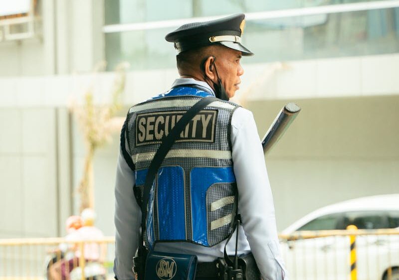 Security guard in uniform standing outdoors on a city street, maintaining public safety.
