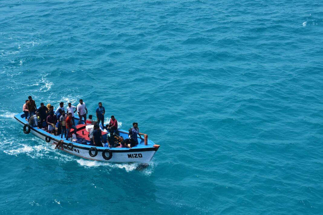 A crowded boat filled with people enjoying a ride on the vivid blue ocean waters in India.