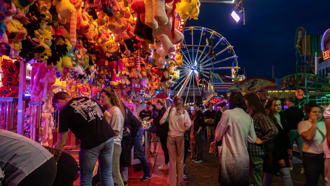 a crowd of people standing around a carnival at night