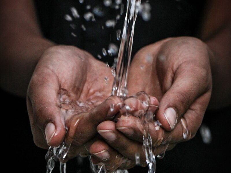 pouring water on person's hands