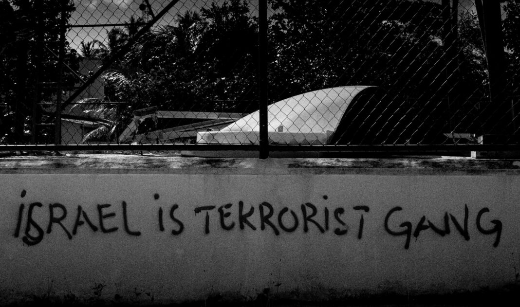 A black and white photo of a fence with graffiti on it