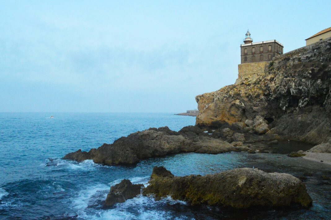 brown concrete building on rock formation near sea during daytime