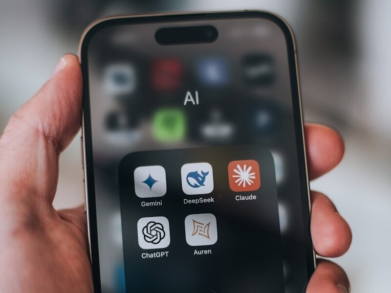 Hand holding a phone with ai application icons.