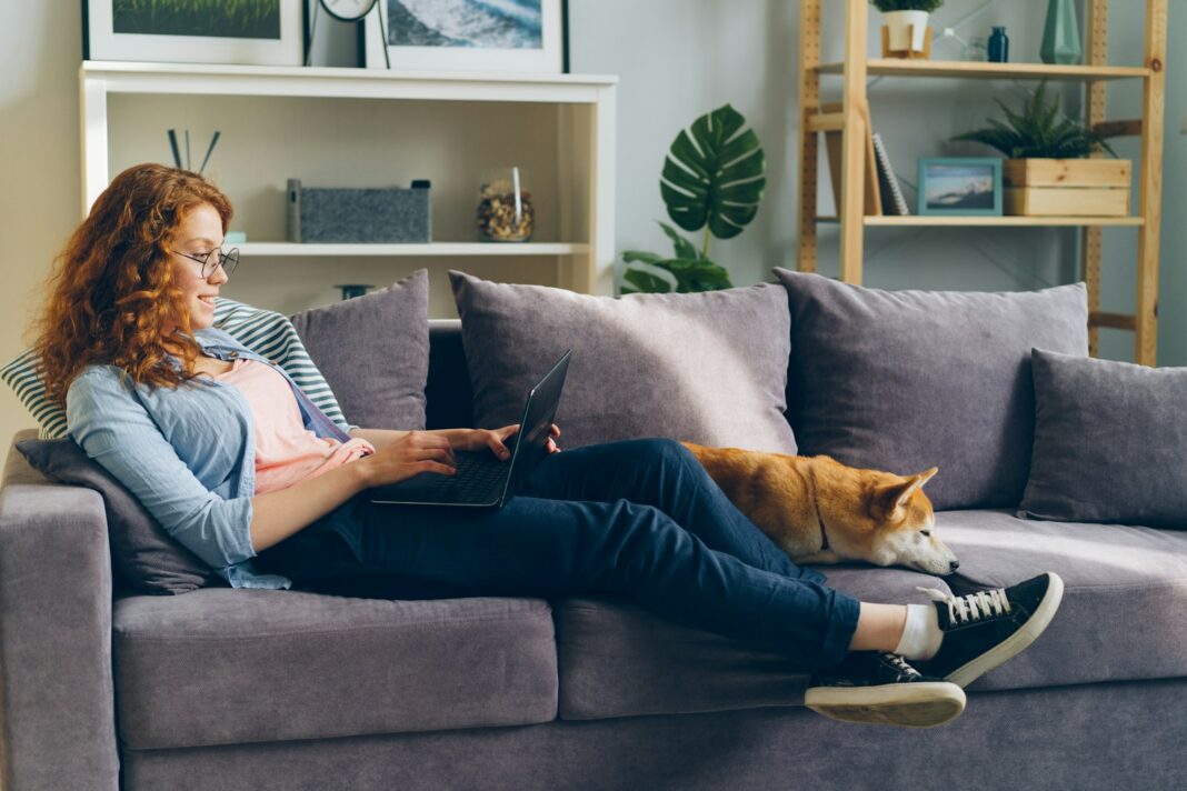 a woman sitting on a couch using a laptop computer