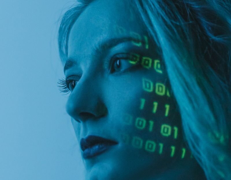 Tech-inspired portrait of a woman with digital code projected on her face, symbolizing cybersecurity.